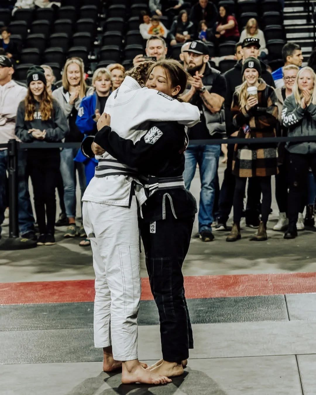 Two Fort teammates embrace at a competition as their community cheers behind them
