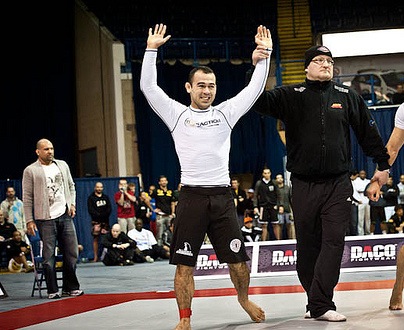Marcelo Garcia celebrating a win at ADCC 2011 with both arms raised beside the referee