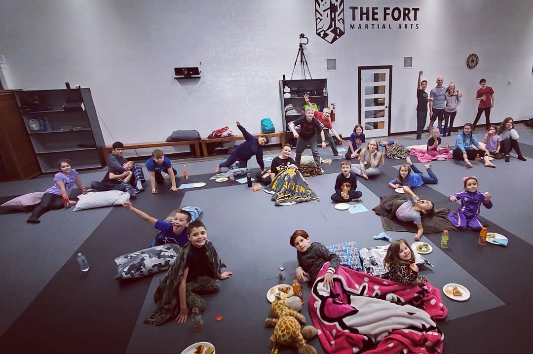 Young Fort members relaxing with blankets and pillows on the mats at their Christmas party