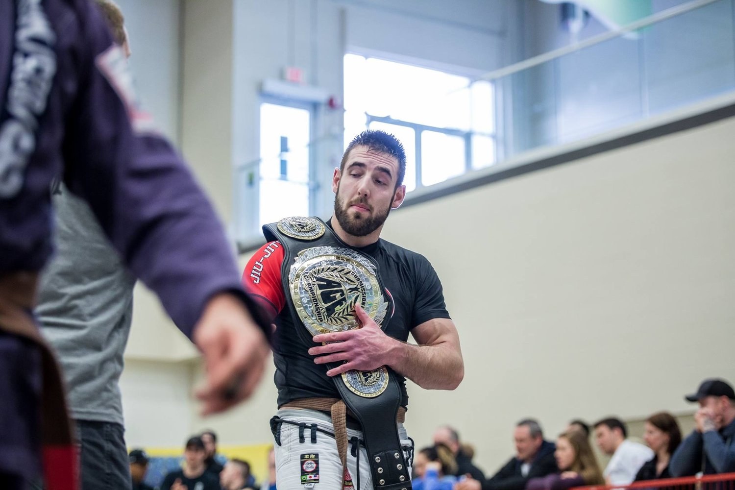 Scott Campbell holding championship belts at a grappling competition